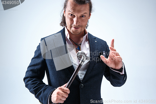 Image of The mature barded man in a suit holding cane.
