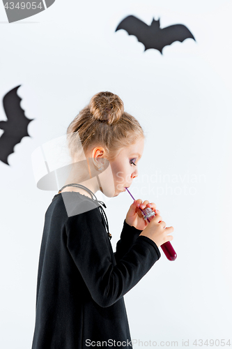 Image of Little girl witch in black dress over magical accessories. Halloween, the studio evening.