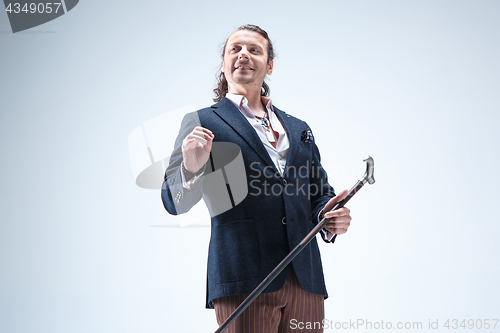 Image of The mature barded man in a suit holding cane.