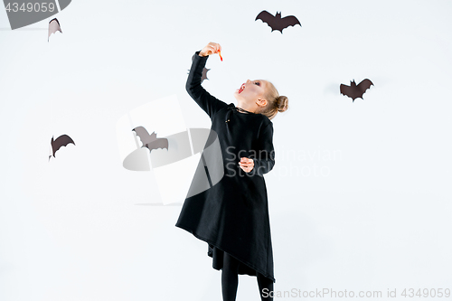 Image of Little girl witch in black dress over magical accessories. Halloween, the studio evening.