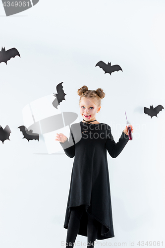 Image of Little girl witch in black dress over magical accessories. Halloween, the studio evening.