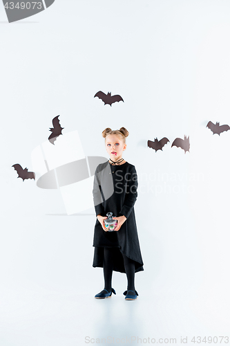 Image of Little girl witch in black dress over magical accessories. Halloween, the studio evening.