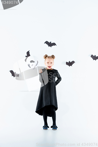 Image of Little girl witch in black dress over magical accessories. Halloween, the studio evening.