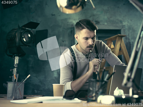 Image of Portrait of a bearded businessman who is checking details of his upcoming meeting in his notebook and typing.