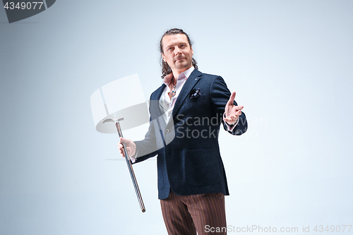 Image of The mature barded man in a suit holding cane.