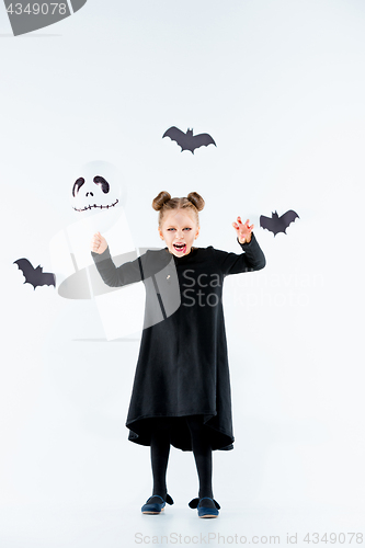 Image of Little girl witch in black dress over magical accessories. Halloween, the studio evening.