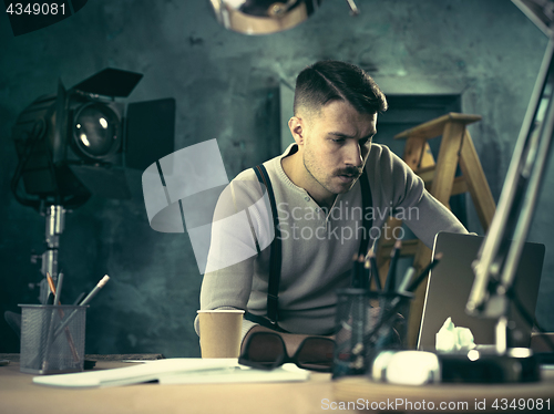 Image of Portrait of a bearded businessman who is checking details of his upcoming meeting in his notebook and typing.