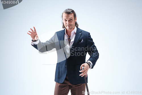 Image of The mature barded man in a suit holding cane.