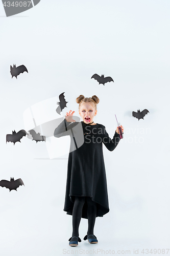 Image of Little girl witch in black dress over magical accessories. Halloween, the studio evening.