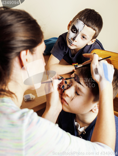 Image of little cute child making facepaint on birthday party, zombie Apocalypse facepainting, halloween preparing concept, lifestyle people babes