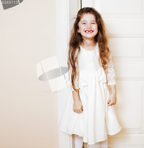 Image of little cute girl at home, opening door well-dressed in white dre