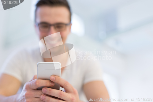 Image of young man using a mobile phone  at home