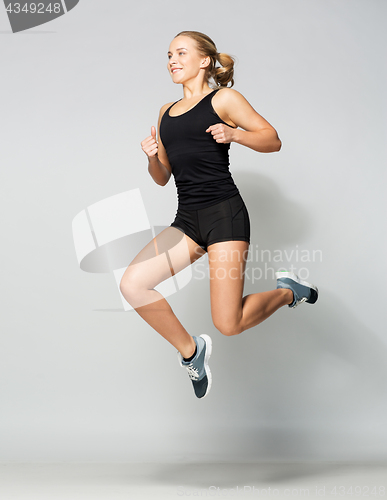 Image of young woman in black sportswear jumping