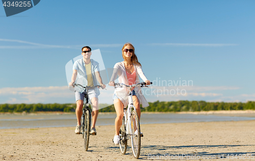 Image of happy young couple riding bicycles at seaside