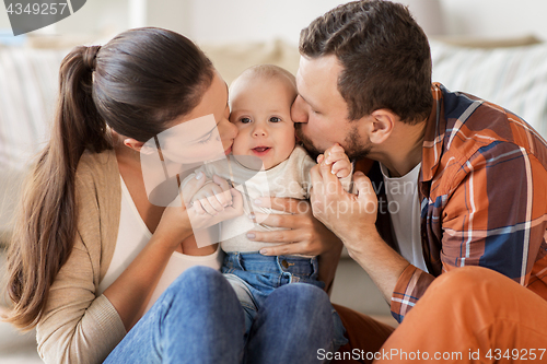 Image of happy mother and father kissing baby at home