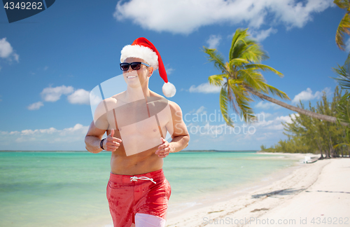 Image of happy man running along summer beach at christmas