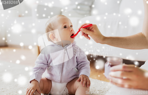 Image of mother with spoon feeding little baby at home