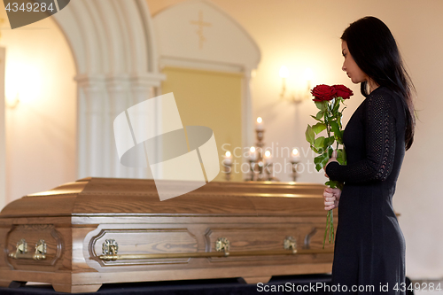 Image of woman with red roses and coffin at funeral