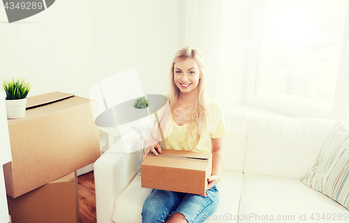 Image of smiling young woman with cardboard box at home