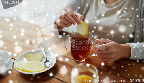 Image of close up of ill woman adding lemon to tea cup