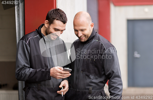 Image of auto mechanics with smartphone at smoking brake