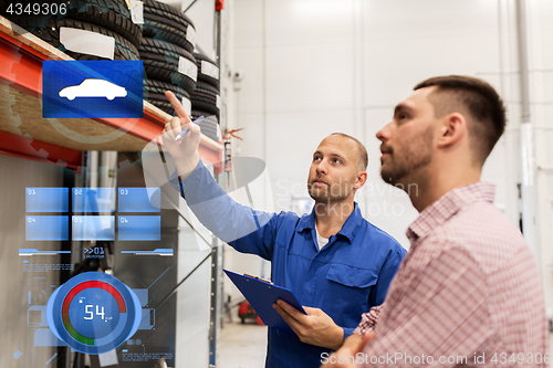 Image of auto mechanic with clipboard and man at car shop