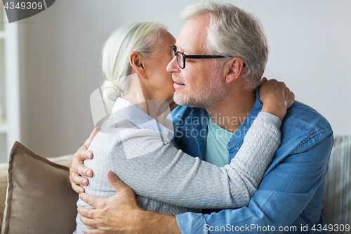 Image of happy senior couple hugging at home