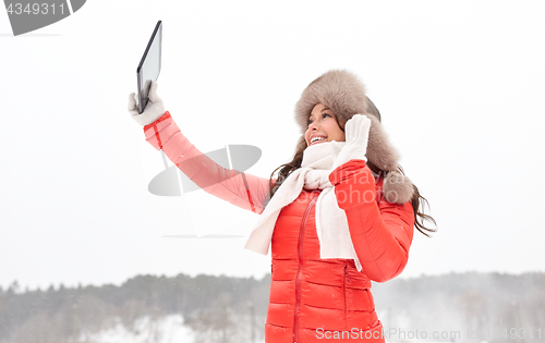 Image of woman in winter fur hat with tablet pc outdoors