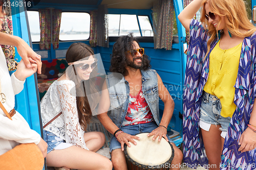 Image of happy hippie friends playing music in minivan