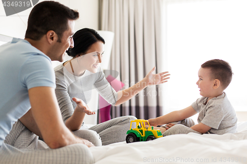 Image of happy family in bed at home or hotel room