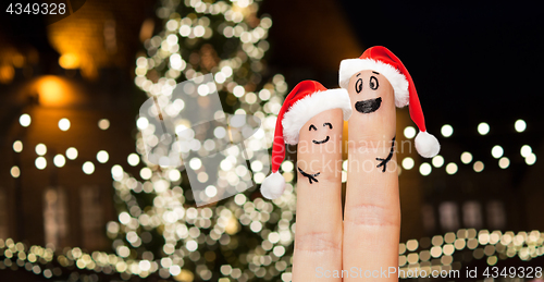 Image of two fingers in santa hats over christmas tree
