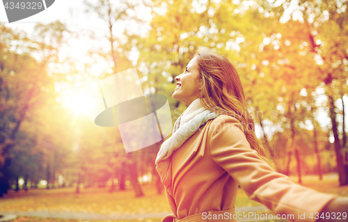 Image of beautiful happy young woman walking in autumn park