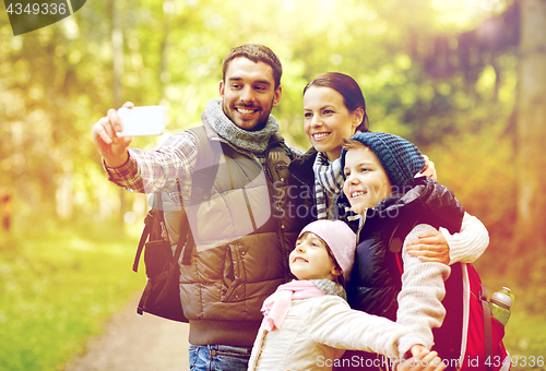 Image of family with backpacks taking selfie by smartphone