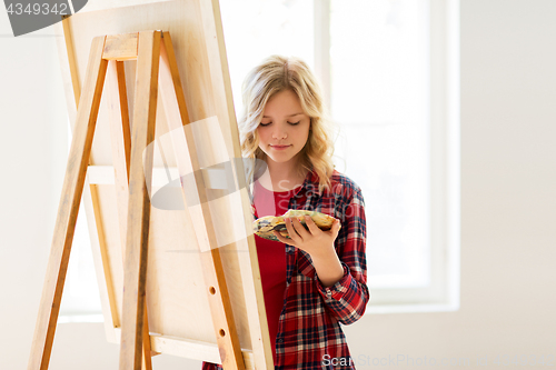 Image of student girl with easel painting at art school