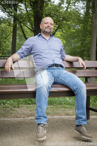 Image of handsome bearded man sitting outdoors