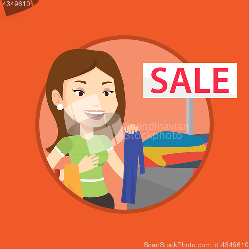 Image of Young woman choosing clothes in shop on sale.