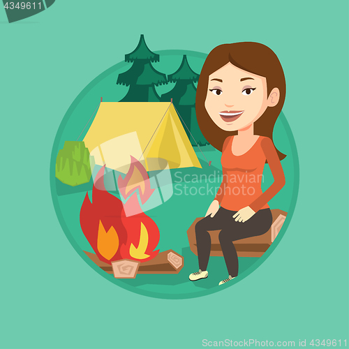 Image of Woman sitting on log near campfire in the camping.