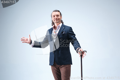 Image of The mature barded man in a suit holding cane.