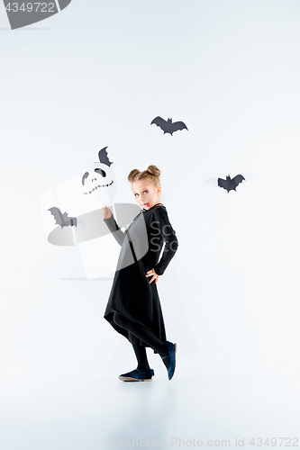 Image of Little girl witch in black dress over magical accessories. Halloween, the studio evening.