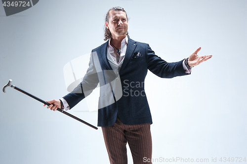 Image of The mature barded man in a suit holding cane.