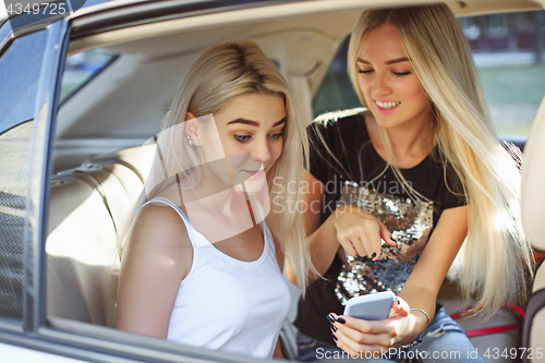 Image of The pretty european girls 25-30 years old in the car make photo on mobile phone