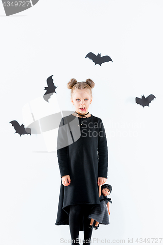 Image of Little girl witch in black dress over magical accessories. Halloween, the studio evening.