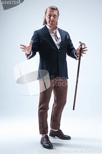 Image of The mature barded man in a suit holding cane.