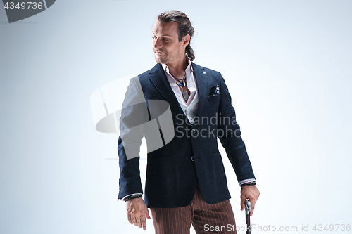 Image of The mature barded man in a suit holding cane.