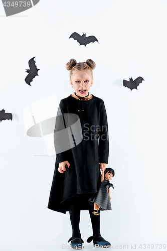 Image of Little girl witch in black dress over magical accessories. Halloween, the studio evening.