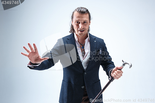 Image of The mature barded man in a suit holding cane.