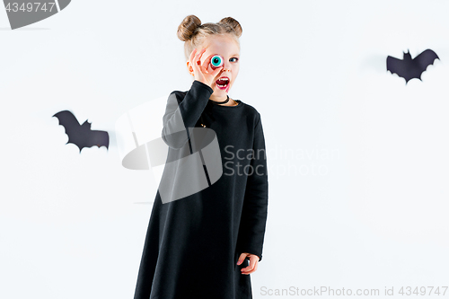 Image of Little girl witch in black dress over magical accessories. Halloween, the studio evening.