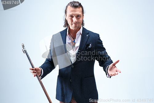 Image of The mature barded man in a suit holding cane.