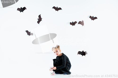 Image of Little girl witch in black dress over magical accessories. Halloween, the studio evening.