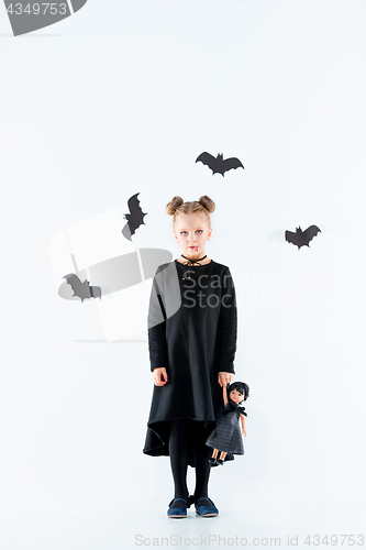 Image of Little girl witch in black dress over magical accessories. Halloween, the studio evening.